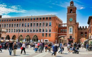 a crowd of people walking around a brick building
