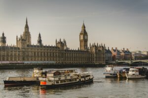 four white boats traveling on river beside Big Ben in London
