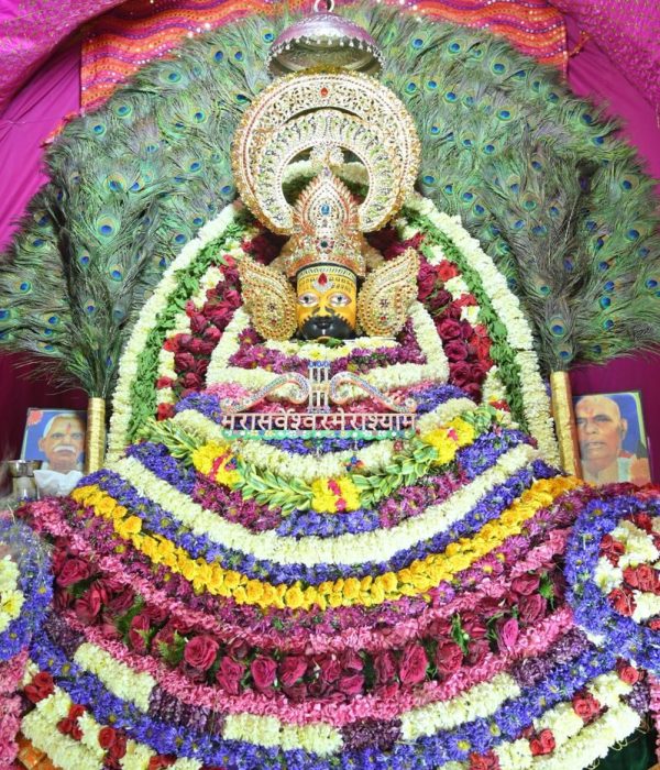 Colorful and intricate Hindu deity decoration adorned with peacock feathers and flowers in Patiala, India.
