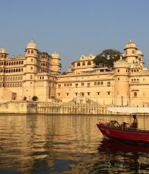 red and white boat on body of water near beige concrete building during daytime