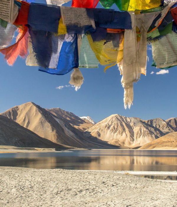 blue yellow and red textile on gray sand near lake and mountain during daytime