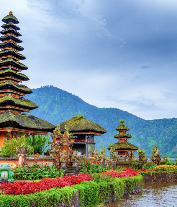 brown and green temple near lake and green mountain under blue sky during daytime